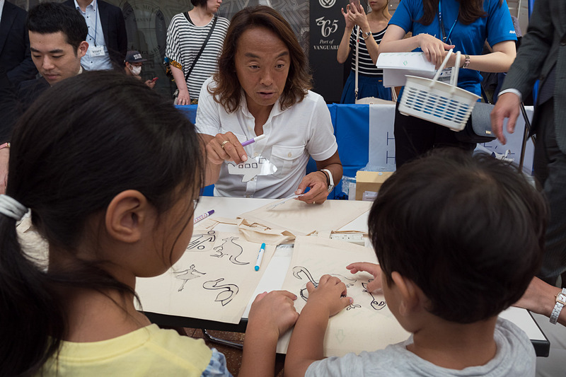 飛行機とサッカーをテーマにした絵を描く北澤氏。まわりの子供たちとも談笑しながら楽しむ様子が見られた