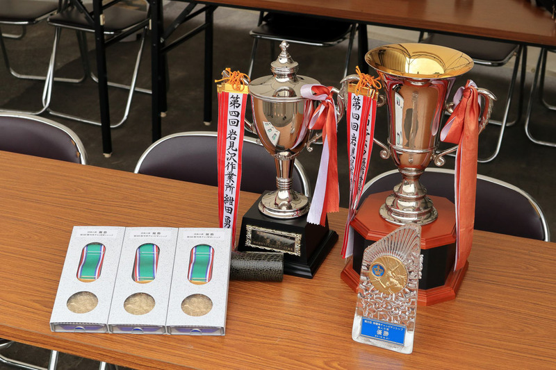 団体の部で優勝した岩見沢事業所チームには優勝杯とメダルが。個人の部で優勝した久保誠一氏には優勝杯と優勝盾が送られた