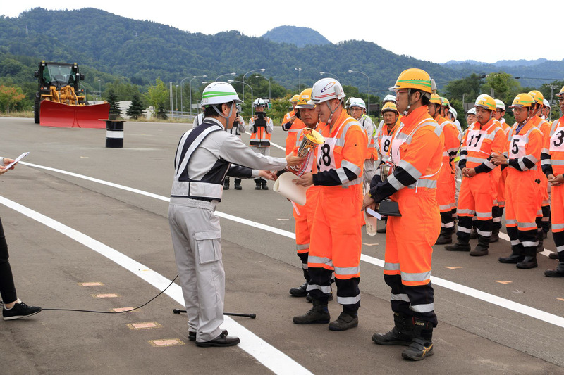団体の部で優勝した岩見沢事業所チームには優勝杯とメダルが。個人の部で優勝した久保誠一氏には優勝杯と優勝盾が送られた