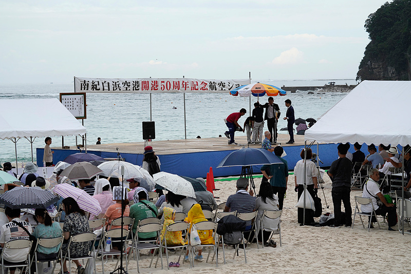 渋滞で到着できなかった和歌山県知事の仁坂吉伸氏に代わり、白浜町長の井澗誠氏が開会のあいさつ。海水浴客以外で白良浜にこれだけの人が集まるのはやはりめずらしいとのこと