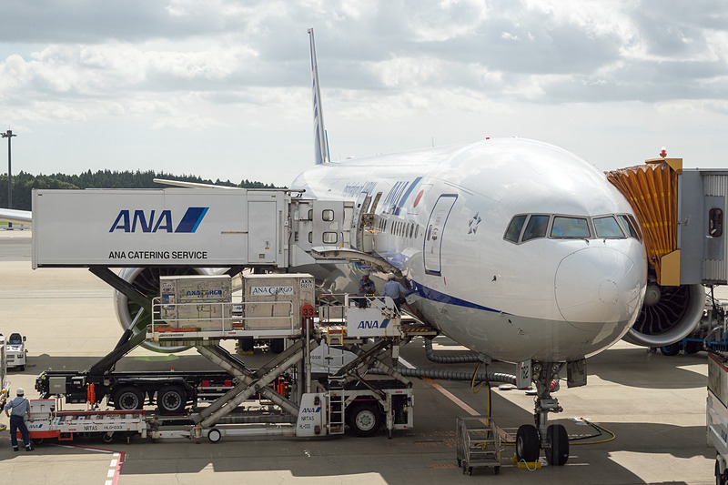 飛行機のまわりでは「宇宙日本食」も入った機内食を積み込むフードローダーなどによる出発準備が進むなか、大西 宇宙飛行士らが搭乗客に搭乗証明書やステッカーを配布