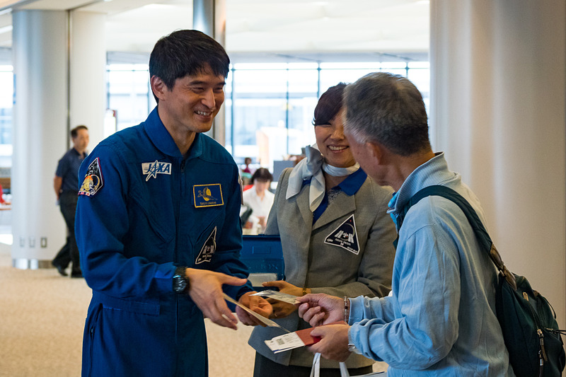 飛行機のまわりでは「宇宙日本食」も入った機内食を積み込むフードローダーなどによる出発準備が進むなか、大西 宇宙飛行士らが搭乗客に搭乗証明書やステッカーを配布