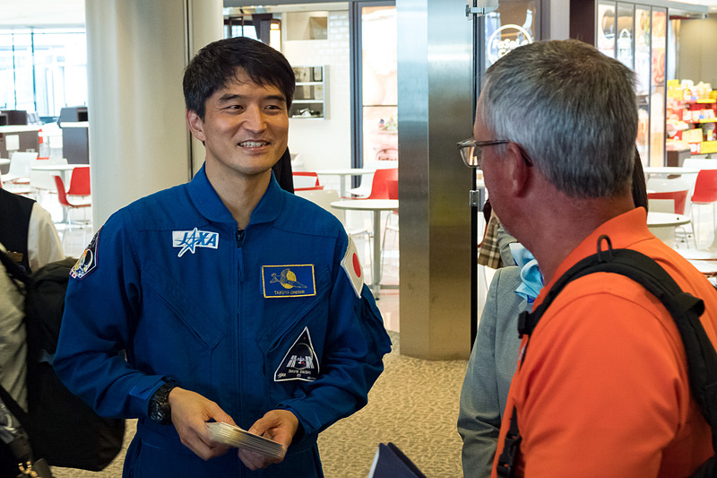 飛行機のまわりでは「宇宙日本食」も入った機内食を積み込むフードローダーなどによる出発準備が進むなか、大西 宇宙飛行士らが搭乗客に搭乗証明書やステッカーを配布
