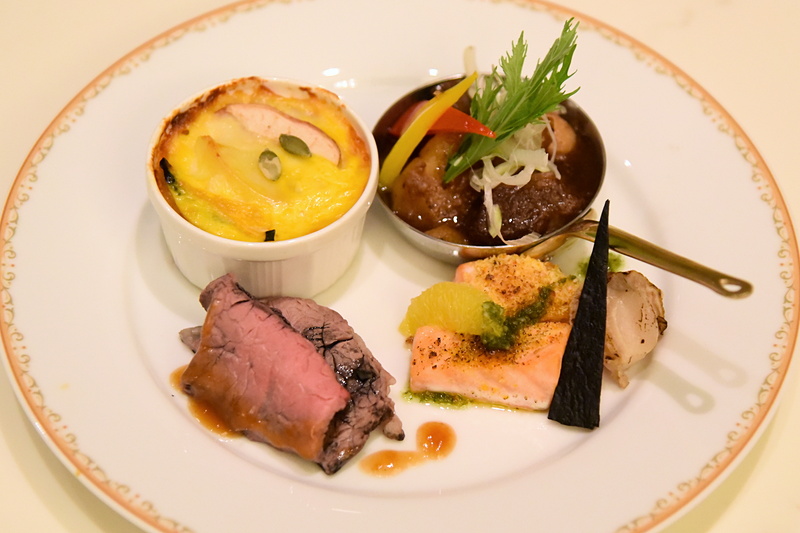 ホットメニューは右上から反時計回りに「ラムスペアリブのブレゼ 黒酢ソース」「カボチャとリンゴのグラタン」「竹炭マリネのローストビーフ」「サーモンと帆立貝のロースト オレンジ風味」