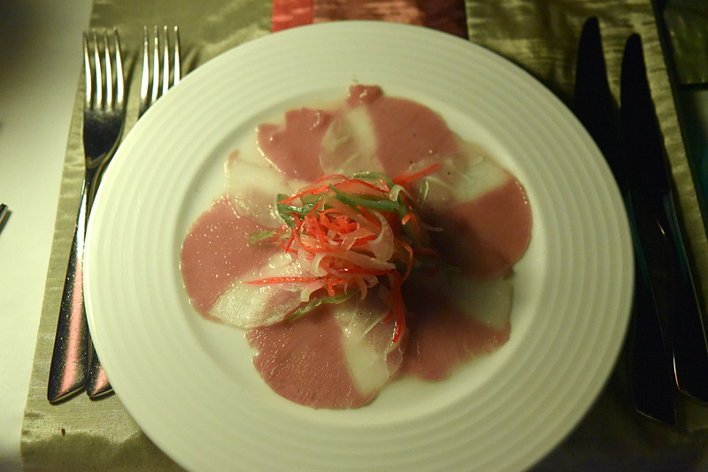 「Thinly Sliced Carpaccio of Smoked Marlin, Sauteed Marinated Baby Octopus, Tiger Prawns Sea Bass and Mussel served with Cocktail Sauce, Kopi Fai and Salad Leaf」