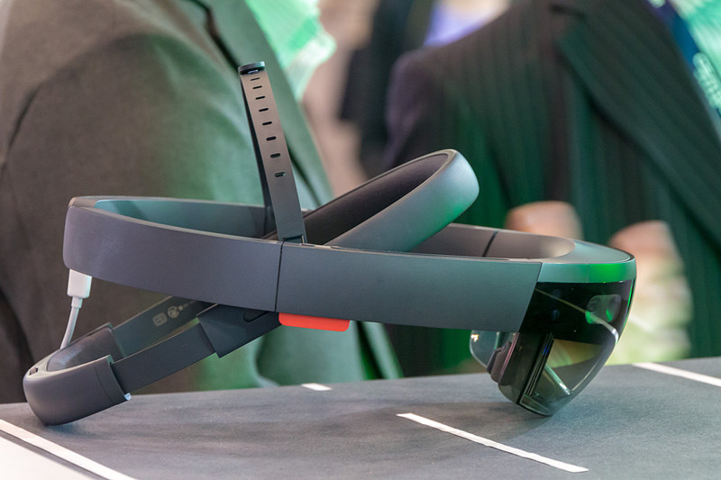 頭部に着用するHoloLens。肉眼で見えている景色にレンズ部に投影された3D画像が重なる。展示コーナーではディスプレイ台の内部が浮き出て見えるように設定されていた