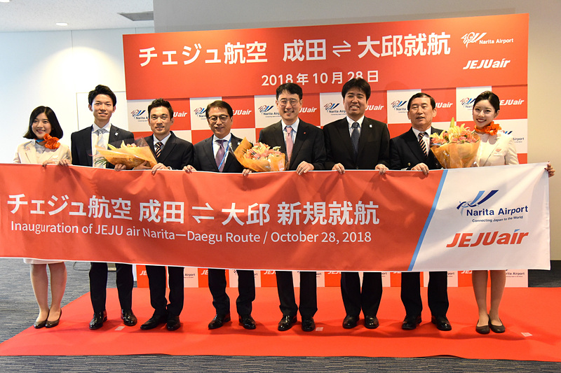 イ・ソックジュ氏、初便の機長と副機長、CA、成田国際空港株式会社 取締役・営業部門長の荒川武氏らが記念撮影