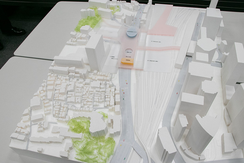 検討会の会場に展示してあった「国道15号・品川駅西口駅前広場整備事業計画」の模型を南側（川崎側）から撮影。国道15号（第一京浜）の右側（東側）の品川駅と左側（西側）を、フタをするような形で巨大なデッキが接続している