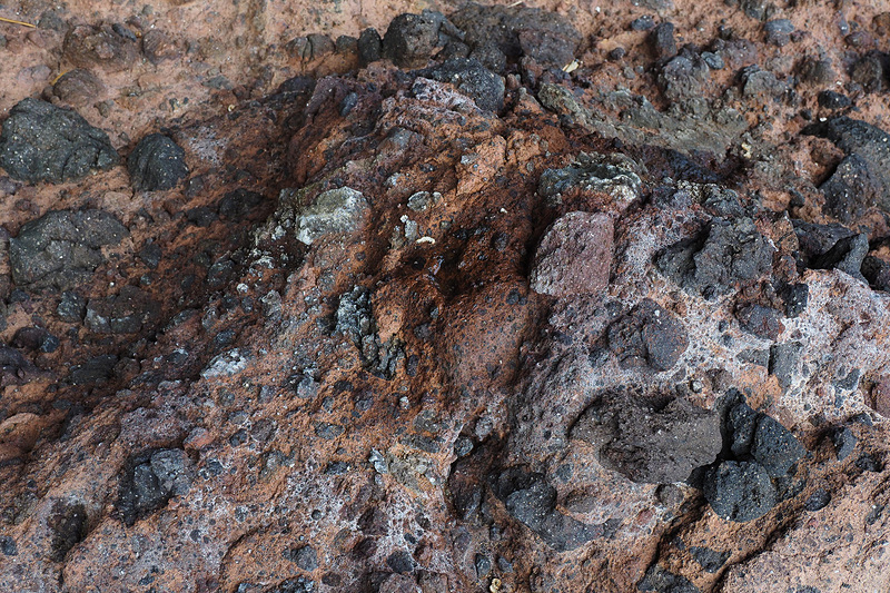 酸化した赤い岩に黒い礫が混入しているようです