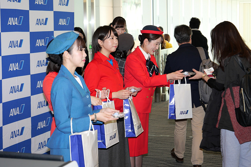 ゲートで乗客へ記念品を手渡した