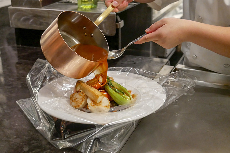 和風ブイヤベースは目の前で調理。透明フィルムを広げた器に具材をのせて、八丁味噌ベースのスープを注ぎます