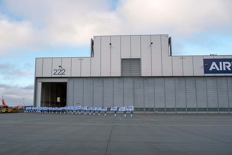 ハンガーのドアが開き始めるとともに、エアバスとANAの旗を持ったチームが登場