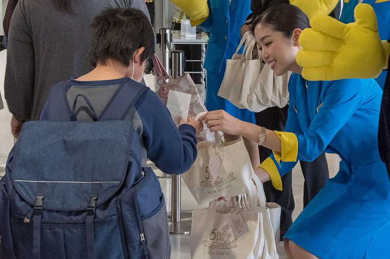 搭乗口で記念品配布のほか、ハイタッチや旗振りで乗客を歓迎