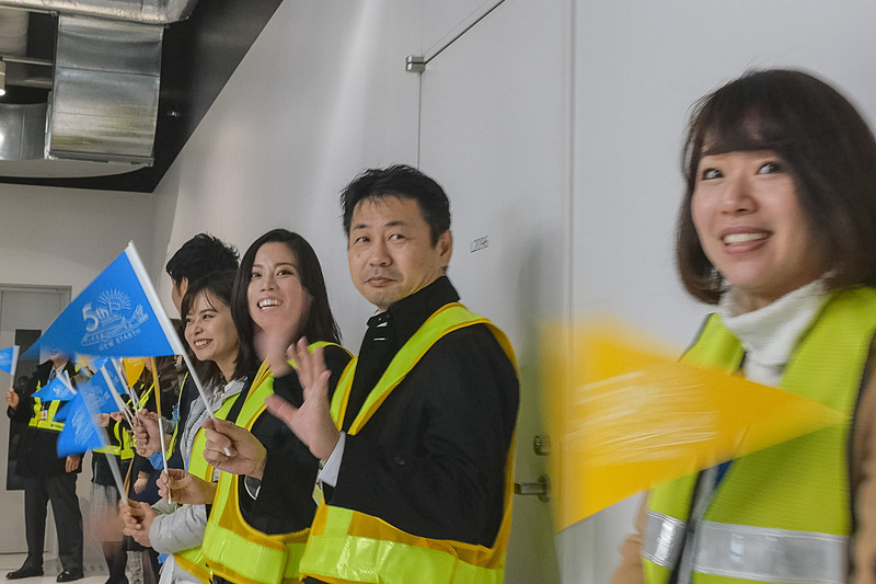 搭乗口で記念品配布のほか、ハイタッチや旗振りで乗客を歓迎