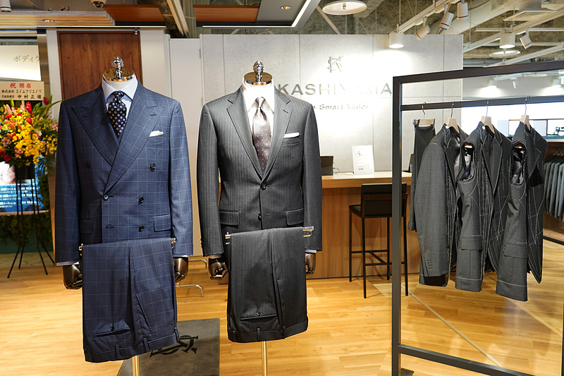 木目調を多く使った店舗デザイン。奥のカウンターはエアラインのチェックインカウンターを意識した作りになっていて、そこで生地やボタン、裏地を見ながら自分に合った一着を選ぶことができる