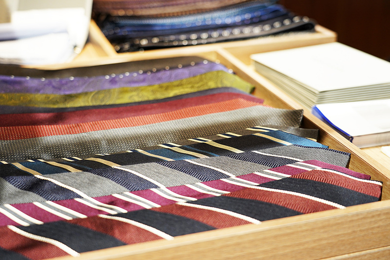 木目調を多く使った店舗デザイン。奥のカウンターはエアラインのチェックインカウンターを意識した作りになっていて、そこで生地やボタン、裏地を見ながら自分に合った一着を選ぶことができる