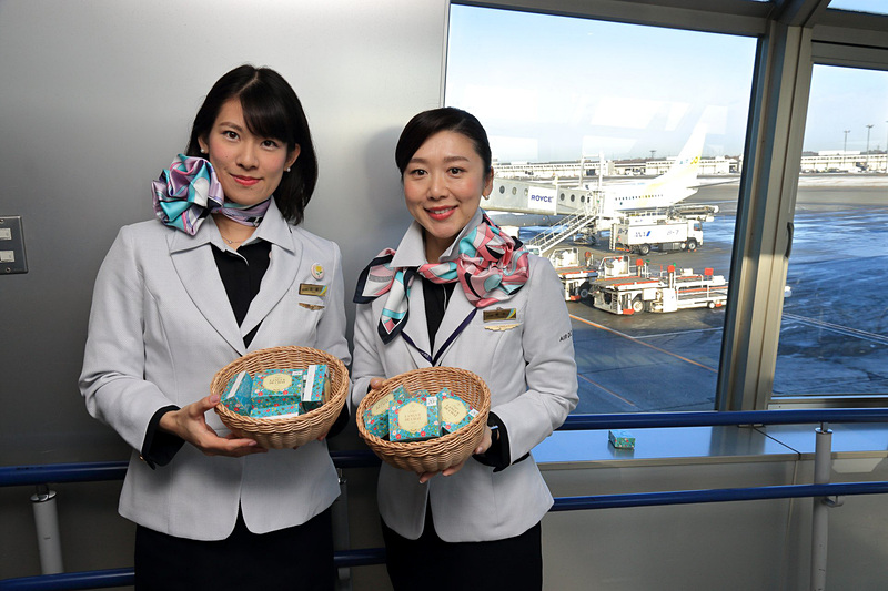 新千歳発便でプレゼントされた石屋製菓の北海道外初の直営店「ISIYA GINZA」限定スイーツ「Saqu（サク）LANGUE DE CHAT」は、「白い恋人」のDNAを受け継いだサクサク食感のラングド・シャで3袋入り。箱にはAIR DO就航20周年のロゴマークシールが貼られていた