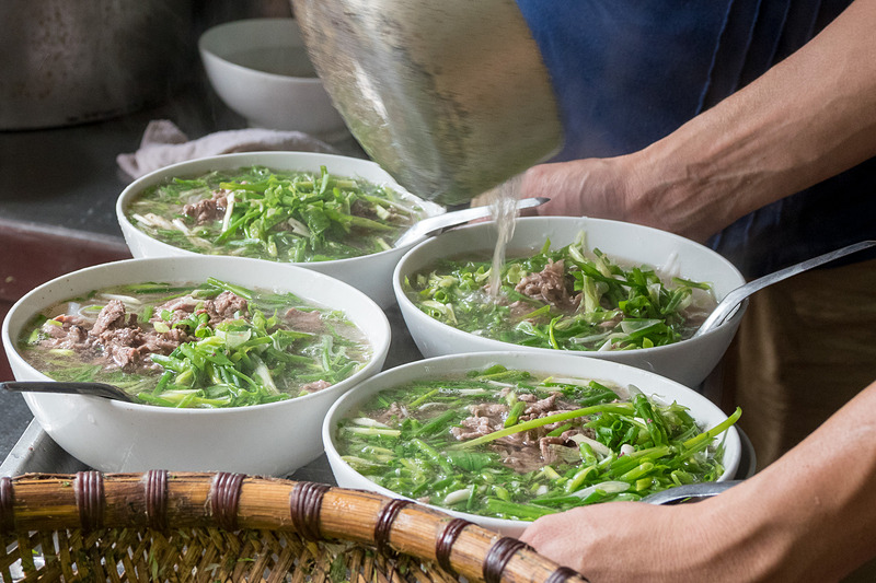 豪快に作られるフォー。客席のパクチーや唐辛子、ライムなどを足してアレンジしたり、揚げパンとともに味わうのがよいそうだ