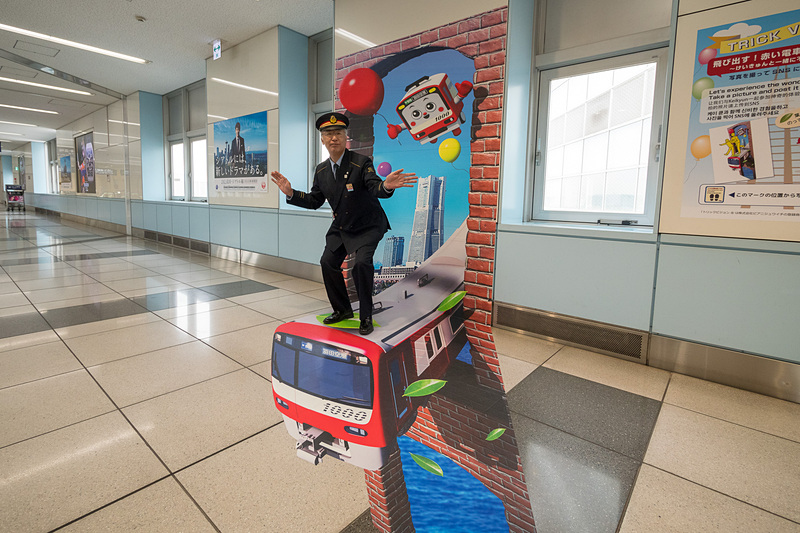 京急が羽田空港国際線ターミナル駅に錯視サインを設置。同じように目の錯覚を利用して京急車両が飛び出すフォトスポットも設置している。ちなみに写真のモデルは、同駅を管轄する京浜急行電鉄株式会社 羽田空港国内線ターミナルの齊藤功司駅長