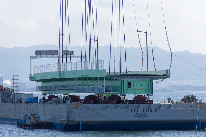 その後、本格的に吊り上げを開始。高さ約15mまで吊り上げ、そのまま武蔵がやや後退した位置で停止。夜までここで待機する。台船は昼間のうちにこの場を離れる