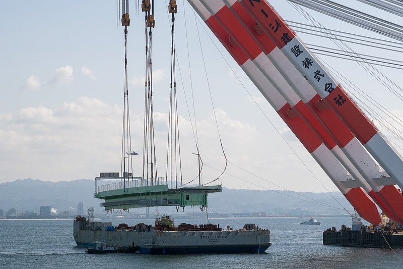 その後、本格的に吊り上げを開始。高さ約15mまで吊り上げ、そのまま武蔵がやや後退した位置で停止。夜までここで待機する。台船は昼間のうちにこの場を離れる