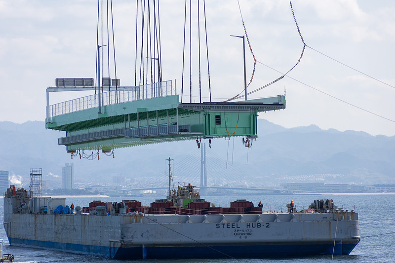 その後、本格的に吊り上げを開始。高さ約15mまで吊り上げ、そのまま武蔵がやや後退した位置で停止。夜までここで待機する。台船は昼間のうちにこの場を離れる