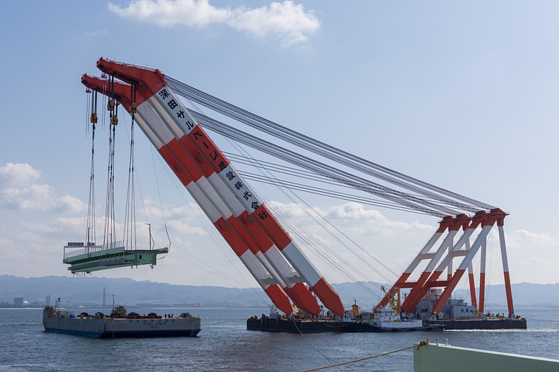 その後、本格的に吊り上げを開始。高さ約15mまで吊り上げ、そのまま武蔵がやや後退した位置で停止。夜までここで待機する。台船は昼間のうちにこの場を離れる