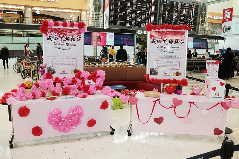 用意された記念写真ブースと、4人組グループが「L・O・V・E」の文字をそれぞれ持ち、JALのスタッフが写真を撮っているところ