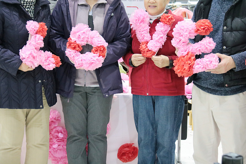 用意された記念写真ブースと、4人組グループが「L・O・V・E」の文字をそれぞれ持ち、JALのスタッフが写真を撮っているところ