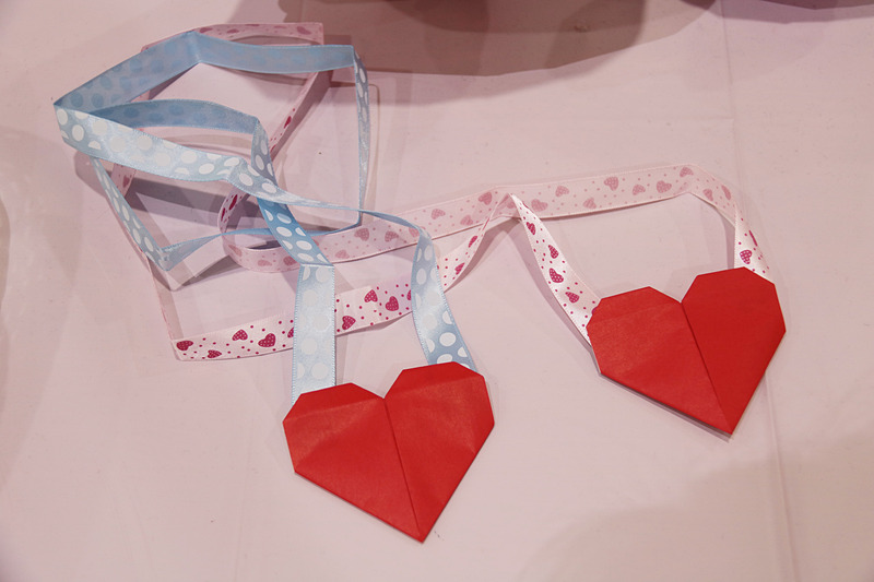 配布されたメッセージ付きキャンディ、当日限定のサプライズ手荷物タグ。ハート折り紙首飾りは、男の子にはブルー、女の子にはピンクがプレゼントされた