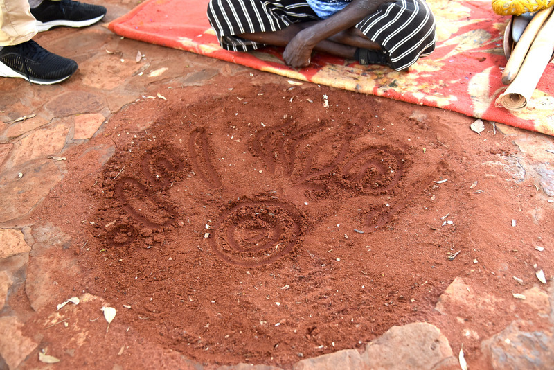 赤土で作られた伝統的なボードに指でモチーフを描きながら講習を行なう
