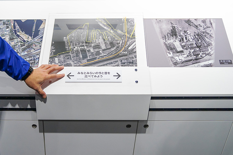 三菱重工造船所とみなとみらい21地区の歩みを紹介する「横浜と三菱重工グループ」。1922年（大正11年）、1956年（昭和31年）、2014年（平成26年）の同地区を航空写真で比較できる