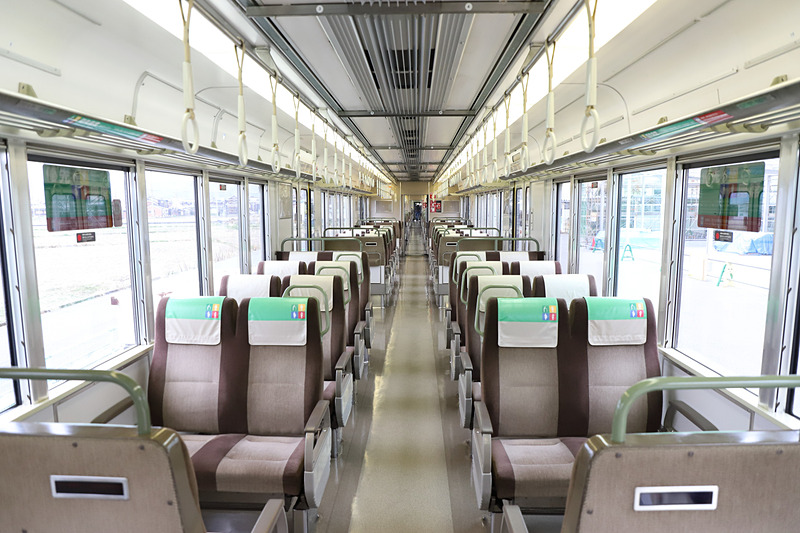 写真左はAシート、写真右は新快速通常車両。壁や床、照明の色を変えたほか、つり革の撤去、シートの変更により特急列車並みの上質な空間を演出した