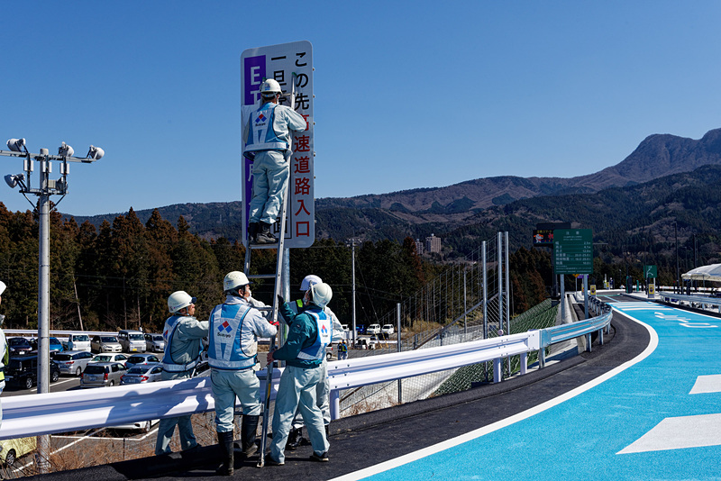 式典、テープカットの後、案内表示の目隠しがはがされるなど開通に向けての準備が進む