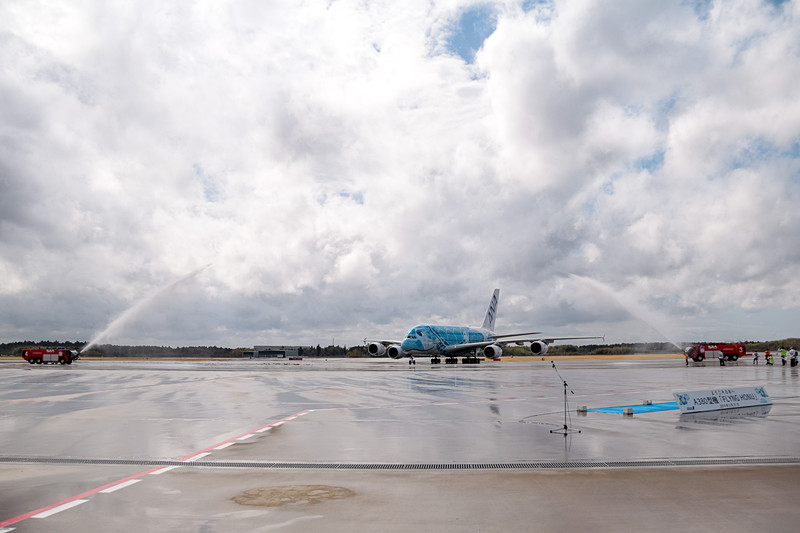 成田空港はウォーターキャノンで同機の到着を歓迎。直前まで降っていた雨は上がっていたが、注意報が出るほどの強風が吹いていたので、放水車からの水はミストシャワーのカーテンのよう