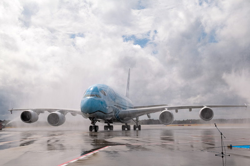 成田空港はウォーターキャノンで同機の到着を歓迎。直前まで降っていた雨は上がっていたが、注意報が出るほどの強風が吹いていたので、放水車からの水はミストシャワーのカーテンのよう