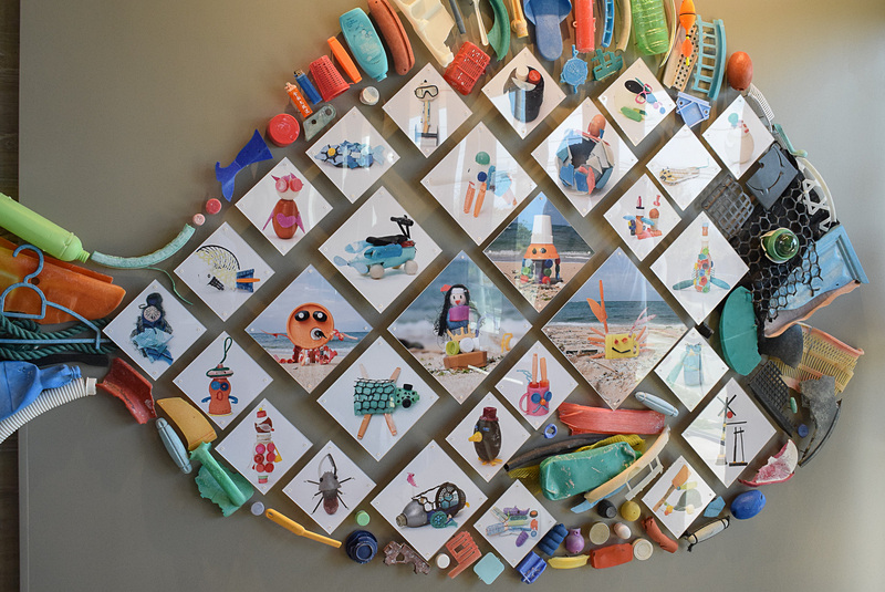 子供たちが作った作品たちの写真を囲むようにプラスチックゴミで魚をかたどっている。「もとぶフローミー」と題された
