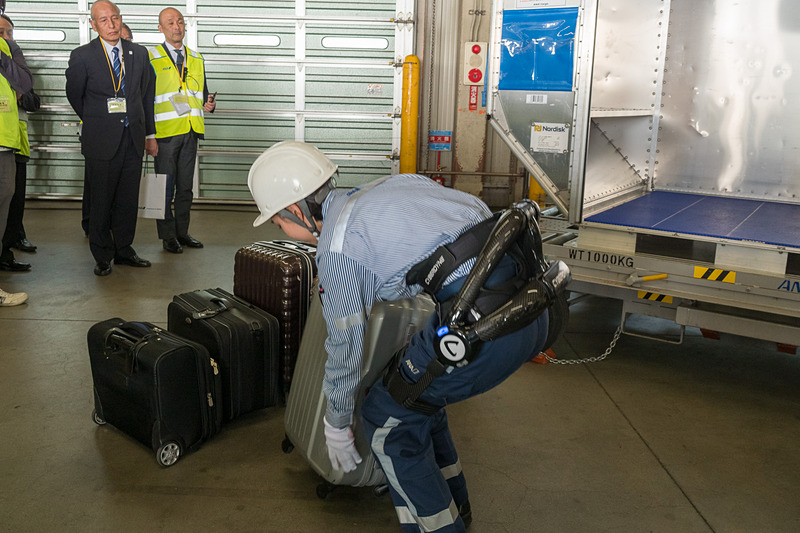 サイバーダイン製のロボットスーツ「HAL」。10kgのおもりを入れたスーツケースを軽々とコンテナに積んでいく様子をデモ。デモをした女性スタッフは「重い荷物を連続して持つことが多いので腰への負担が大きかった。ロボットスーツを使うことで、半分ぐらいの力で持ち上げられる」とコメント