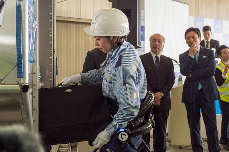サイバーダイン製のロボットスーツ「HAL」。10kgのおもりを入れたスーツケースを軽々とコンテナに積んでいく様子をデモ。デモをした女性スタッフは「重い荷物を連続して持つことが多いので腰への負担が大きかった。ロボットスーツを使うことで、半分ぐらいの力で持ち上げられる」とコメント