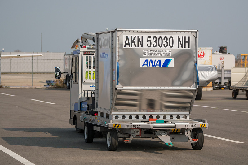 コンテナが乗ったドーリーを運搬する自動運転トーイングトラクター。デモでは1台のドーリーを引いているが最大6台を連結するという