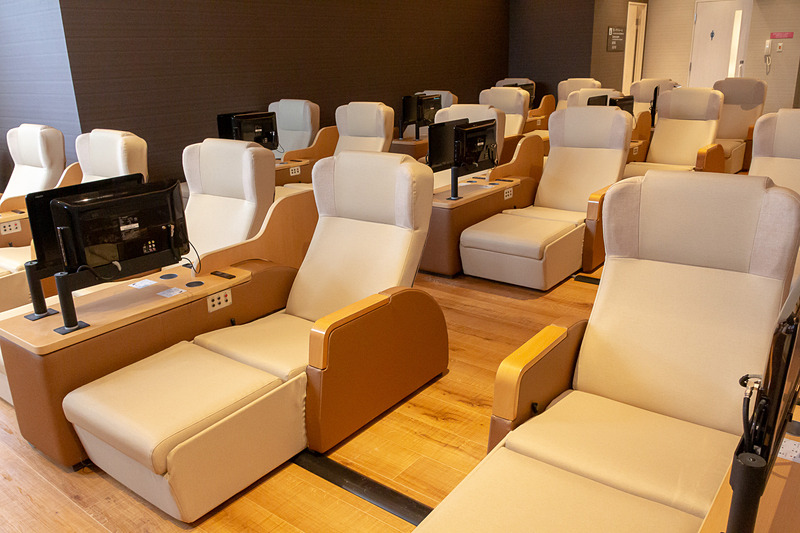 男女共用リラックスラウンジ。テレビ付きチェア50席、フルフラットリクライニング10台を用意