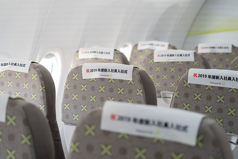 機内に入ると全座席に「Congratulations！」と書かれたヘッドレストカバー。後ろ側には「祝2019年度新入社員入社式」と書かれています