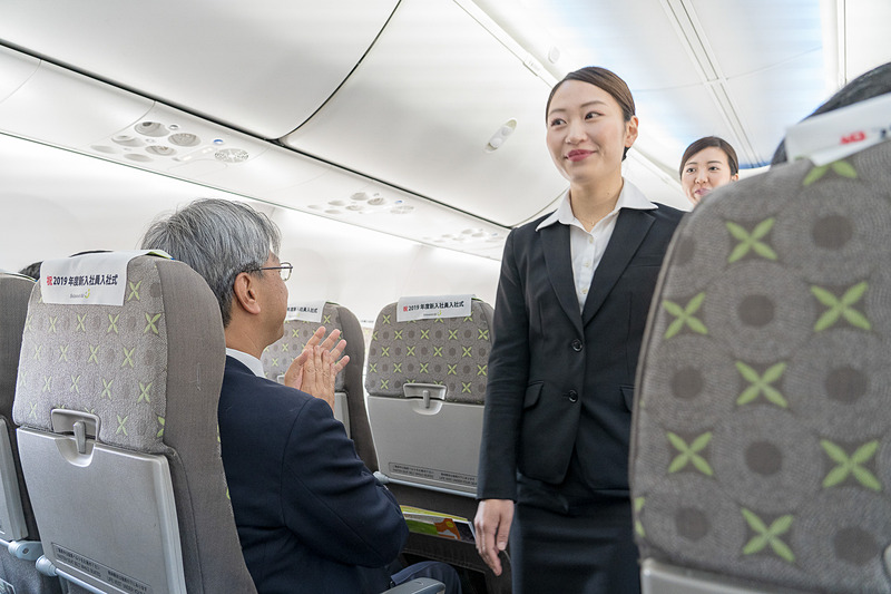 役員らの拍手に迎えられ緊張した面持ちで入場する新入社員の皆さん