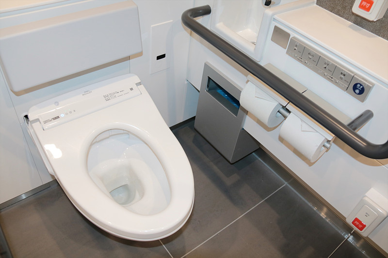 こちらがexperience TOTOの多機能トイレの内部。便座の右奥壁面に埋め込まれているのがスピーカー兼マイクユニット。ドア上部には開閉センサー、天井には人感センサー
