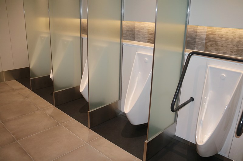 こちらは男性用小便器。隣との間の曇りガラスも大きめ。近寄ると、こぼさないようにターゲットを青色で表示する便器や、消臭効果の高い床材を使用