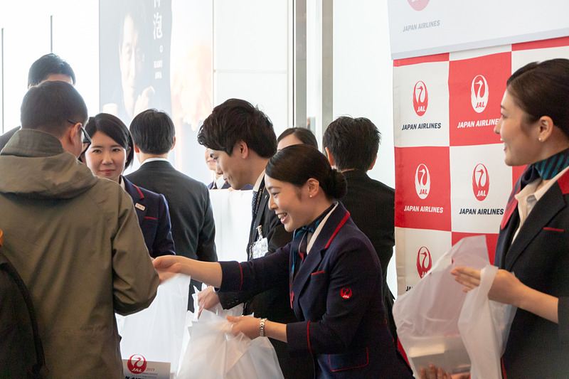 乗客にはポストカードやボールペン、メモ帳などが入った記念品が手渡され、植木会長も並んで乗客を見送った