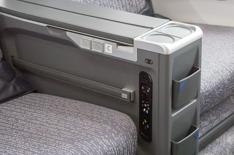 アームレストの下に収納ポケット。側面に機内エンタメのコントローラや、背もたれ＆レッグレストのロックを解除するためのボタンを備える