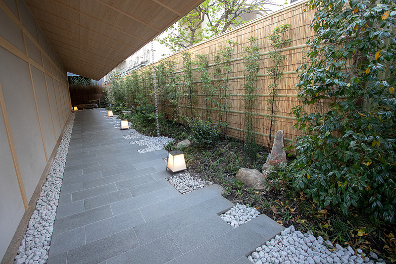 軽く身体を傾けつつ手でのれんを払うようにくぐる、絶妙の高さに設定された暖簾をくぐると玄関までは「和」を感じられる通路となる