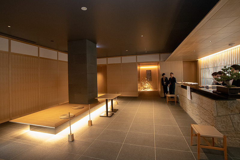 「ONSEN RYOKAN 由縁 新宿」のフロント。カウンターの後ろの壁は雪見障子ふうのデザインになっていた。障子越しには竹のシルエットが見える