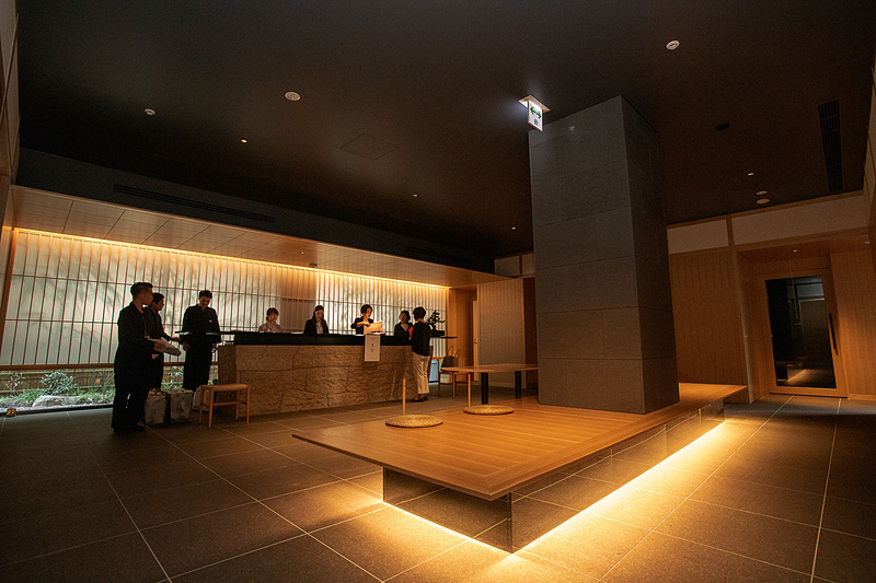 「ONSEN RYOKAN 由縁 新宿」のフロント。カウンターの後ろの壁は雪見障子ふうのデザインになっていた。障子越しには竹のシルエットが見える